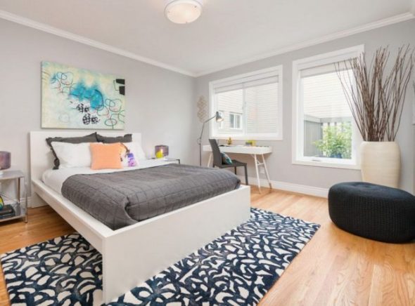 جدران رمادية وتجريد مشرق في غرفة نوم حديثة.