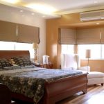 سرير ذو ظهر منحني في غرفة الزاوية مع نوافذ كبيرة