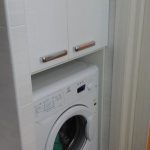 Niche di bilik mandi dengan mesin basuh dan kabinet di atasnya