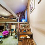 غرفة أنيقة طويلة مع سرير في الأعلى