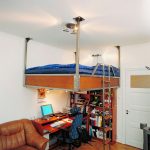 سرير على دعامات معلقة مع طاولة عمل في الطابق السفلي