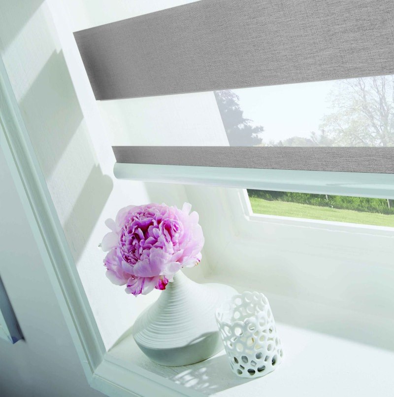 زهرة وردية في مزهرية على عتبة النافذة البلاستيكية