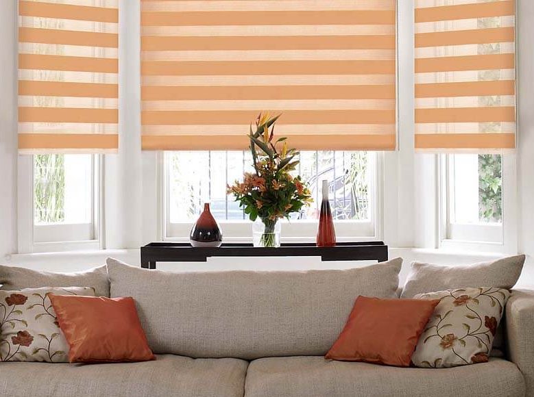 أريكة رمادية بالقرب من النافذة مع الستائر الدوارة