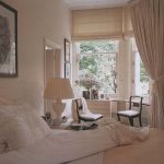 على نافذة الزاوية في غرفة النوم تبدو الستائر الرومانية كبيرة.