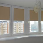 الستائر الدوارة البيج على نوافذ الشرفة البيضاء