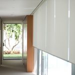 الستائر الدوارة البيضاء على نافذة كبيرة في ممر ضيق