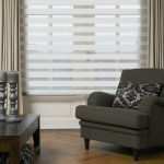 كرسي رمادي في غرفة مع ستائر مخططة